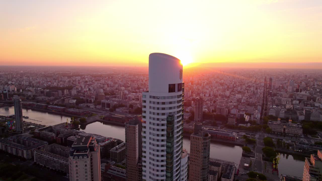 Aerial boom up view of the Alvear Tower with the sun in the background reflecting rays through the building structure, Puerto Madero, Argentina