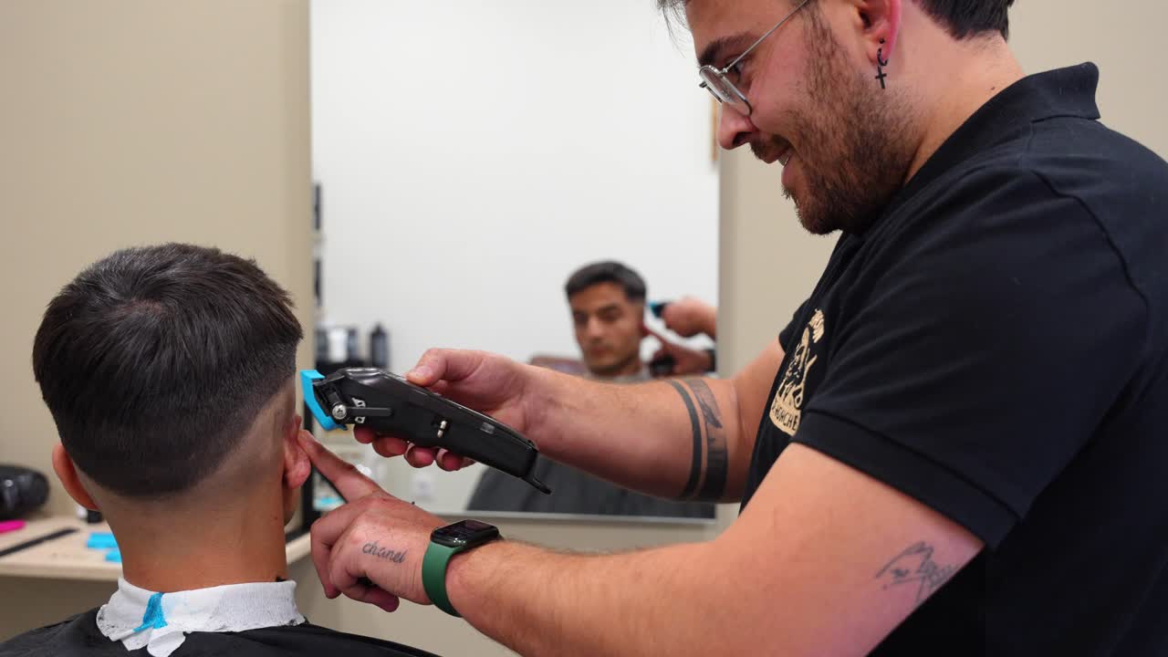 Close up shot of a cheerful barber using a trimmer and smiling during haircut service