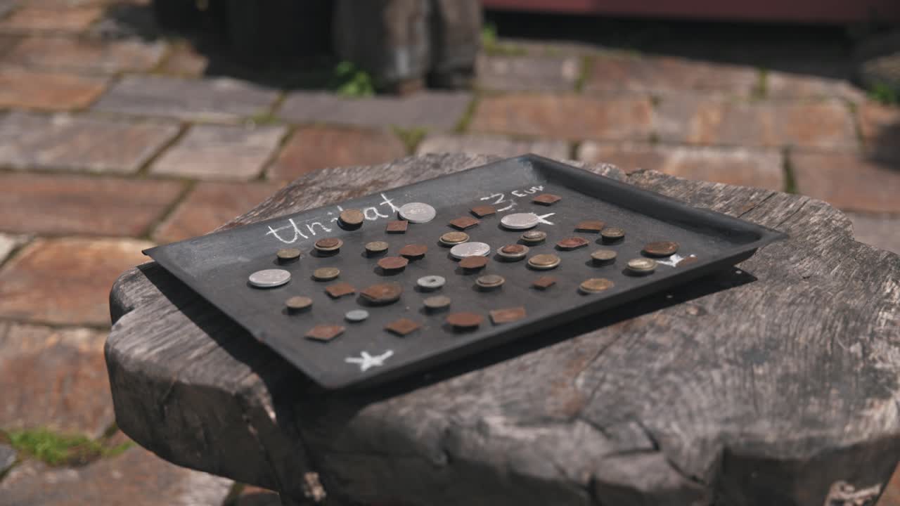 cerca de una bandeja con monedas antiguas etiquetadas "unikat" en una superficie de madera en el mercado de artesanías tradicionales de varaždin