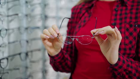 stylish eyeglasses in woman's hands. female buyer holding new spectacles in the optical store. close-up.