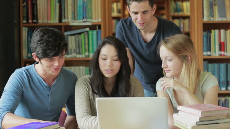 Estudiantes-Viendo-Algo-En-Una-Computadora-Portátil-En-La-Biblioteca