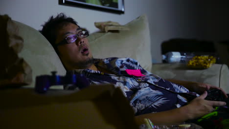 young guy laying on a couch playing video games