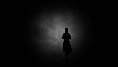 a modern youth dance performed by a graceful and sexy female silhouette, in the smoke against the backdrop of spotlights