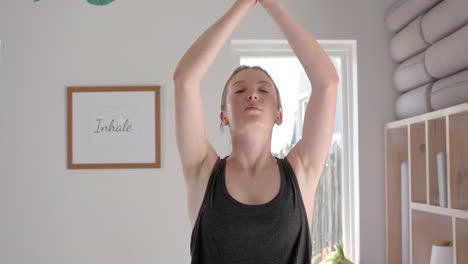 focused caucasian fitness woman practicing yoga in white room, slow motion