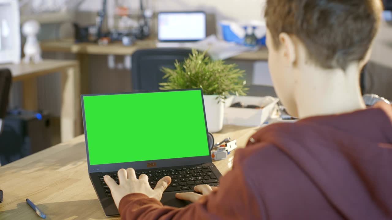 un chico inteligente usa una computadora portátil con una pantalla verde en su clase de ciencias de la computación.