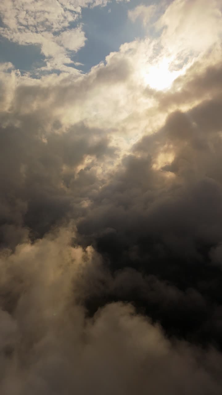 Dark storm clouds part as sunlight breaks through, captured in a vertical dolly shot