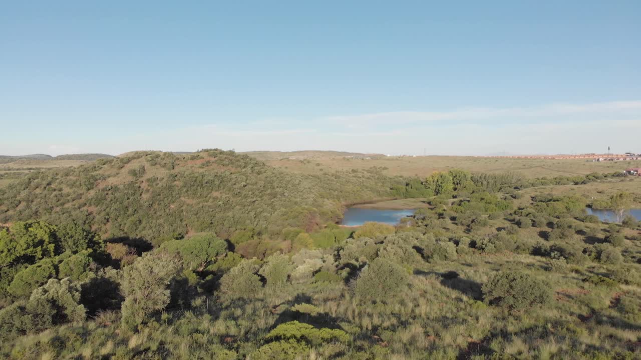 toma aérea inversa de una presa en un valle verde con vivienda en la parte posterior