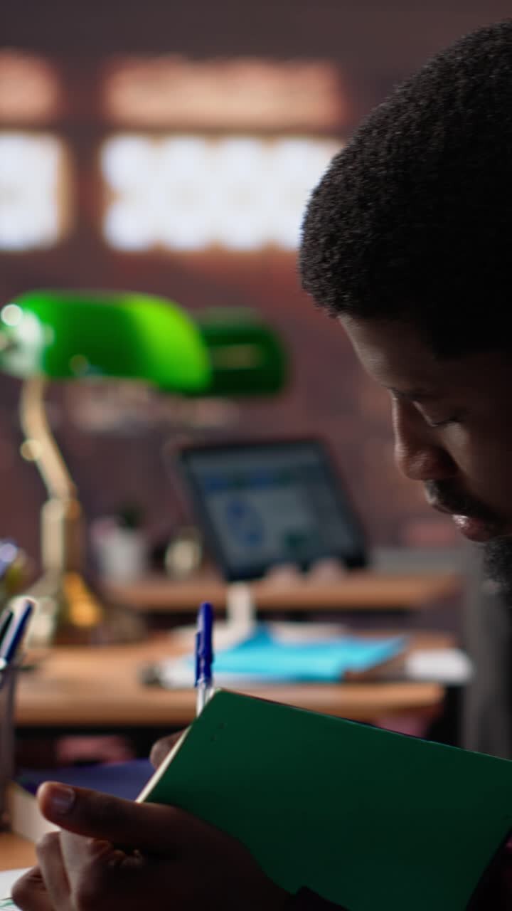 Video verticale: ragazzo afroamericano studia per un esame di diritto cruciale e legge libri specialistici