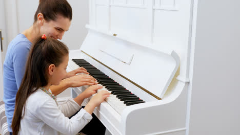 mother assisting daughter in playing piano 4k