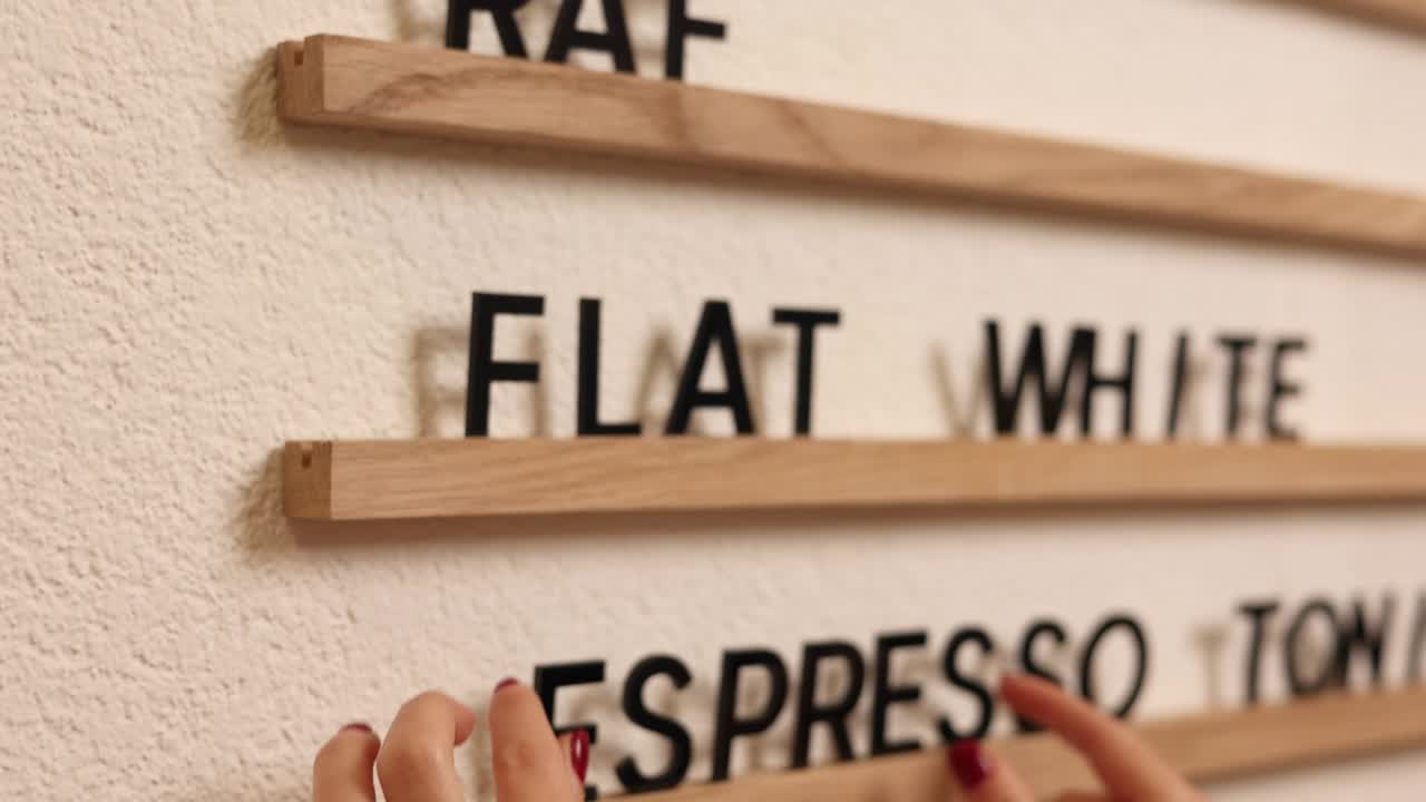 Person arranging coffee menu display