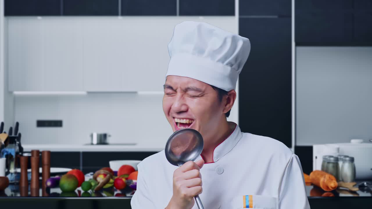 Close Up Of Asian Man Chef Holding Ladle And Singing While Standing In Home Kitchen