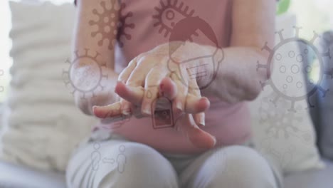 animación de iconos del virus covid 19 sobre una mujer caucásica desinfectando las manos
