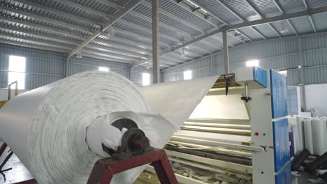 white textile fabric being rolled in factory