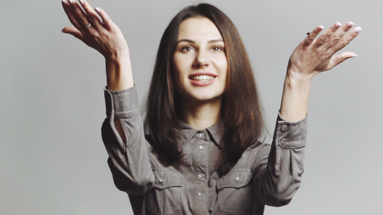 Woman blowing confetti away. Joyful party girl standing and blowing confetti and looking at camera