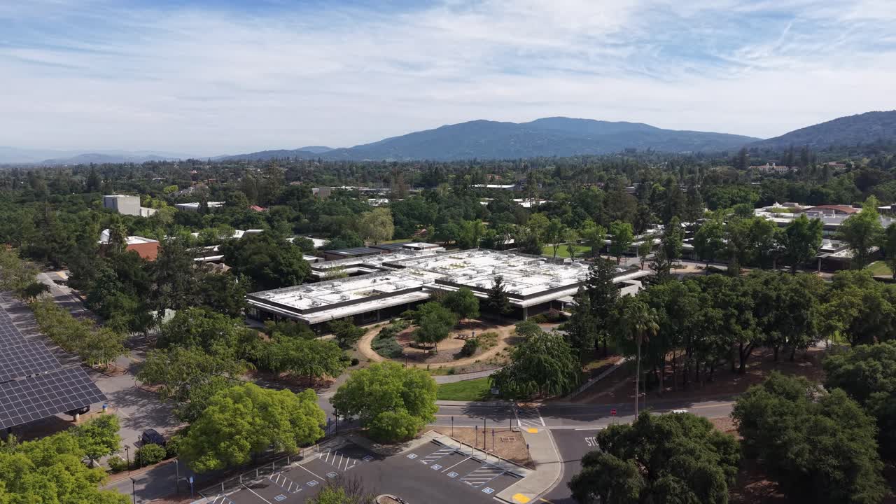 Imágenes de Dron de Ascenso Lento que Muestran el Campus de West Valley College, sus Edificios Rodeados de Exuberantes Árboles Verdes, un Estacionamiento Vacío y las Montañas de Santa Cruz al Fondo