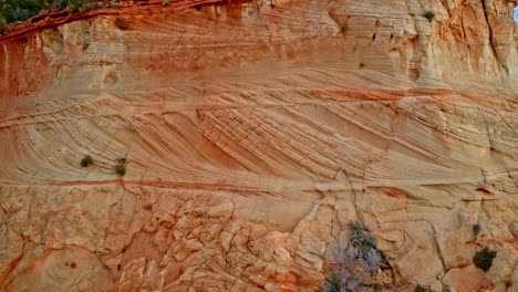 aerial shot gliding over unique formations carved into the red canyon cliffs.