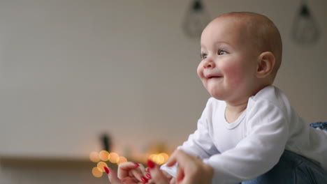 mother plays with baby in a white t-shirt lying on the bed, a child flies and laughs