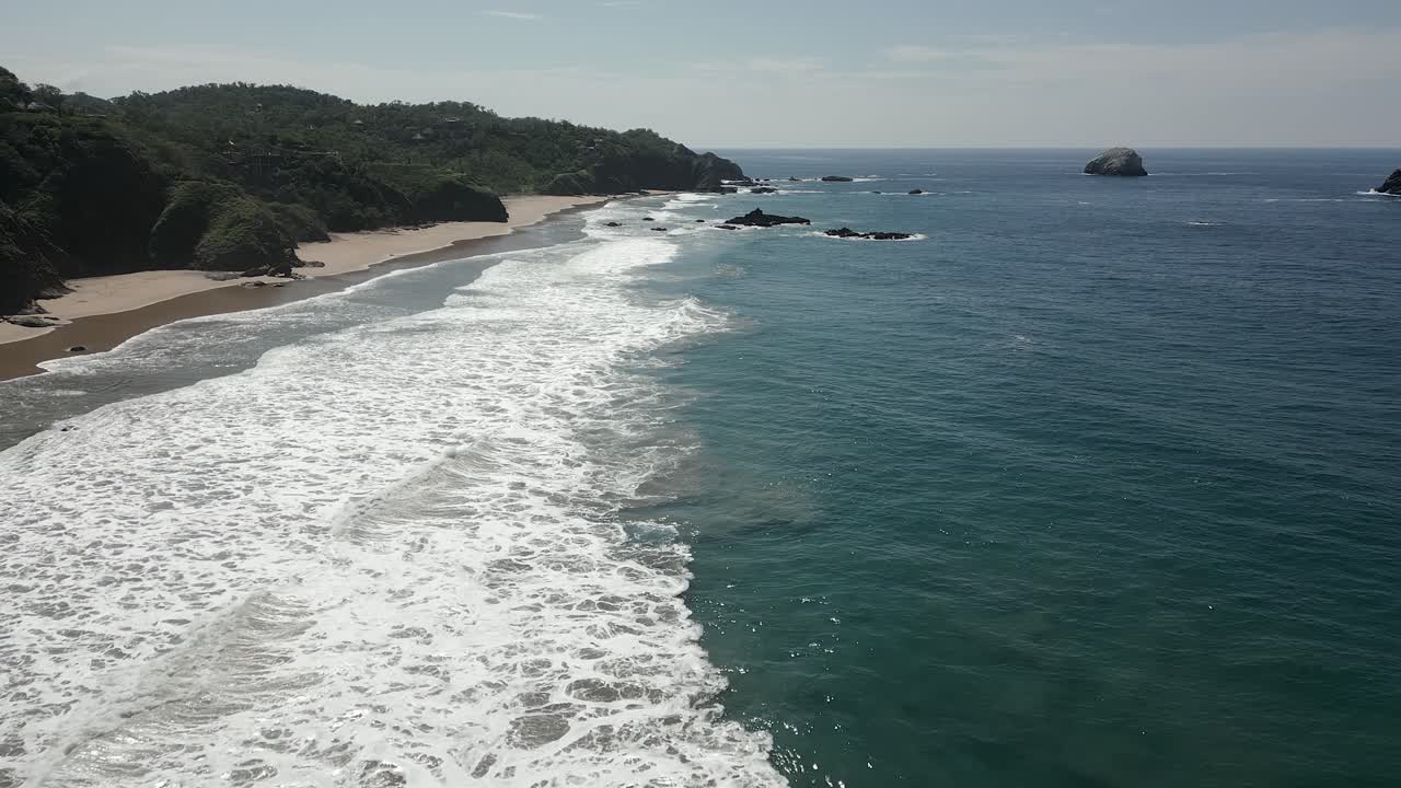 Onde dell'oceano lambiscono dolcemente un'ampia distesa di spiaggia sabbiosa deserta