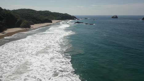 ocean waves gently lap at wide expanse of sand beach with no people