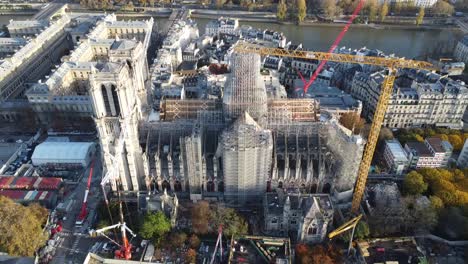 Dron-Con-Movimiento-Hacia-Atrás-Lejos-De-La-Iglesia-De-Notre-Dame-En-París-Durante-La-Renovación,-Muchas-Grúas,-El-Río-Sena-Al-Fondo