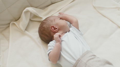 Adorable-Bebé-Recién-Nacido-Acostado-En-La-Cama-Con-Un-Muñeco-En-La-Boca-Mientras-Su-Hermana-Pequeña-Se-Acerca-Y-Lo-Abraza