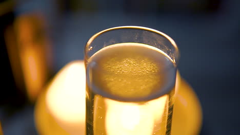 glassware filled with bubbly champagne, blurred candlelights in background