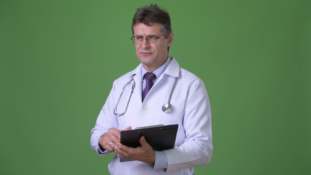 Medico uomo maturo e di bell'aspetto su sfondo verde.
