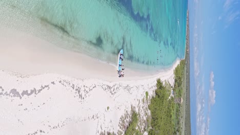 vertical orbit shot of bahia de las aguilas with tourist leaving boat after trip on caribbean sea in sunlight