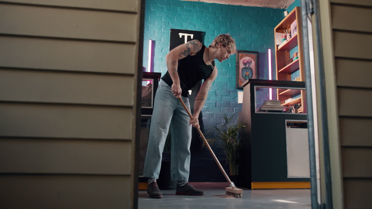 A man sweeping the floor of a tattoo studio
