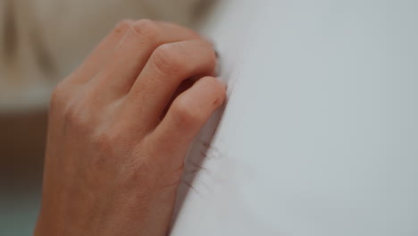 woman's hand sewing or fastening a zipper on a white garment
