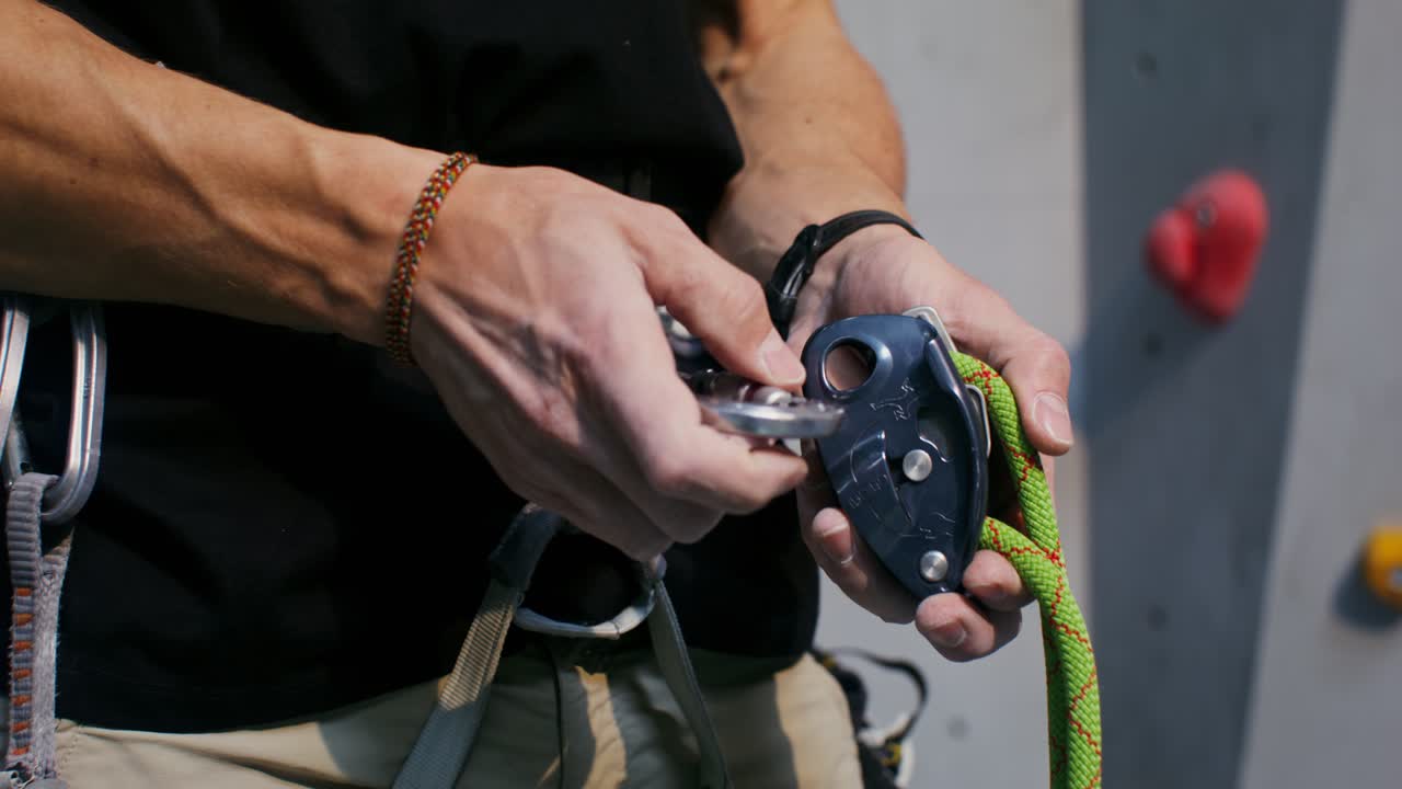 Scalatore di roccia che regola l'attrezzatura da arrampicata