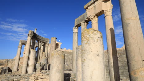 Ancient-Roman-columns-stand-tall-against-a-clear-blue-sky-in-Dougga,-Tunisia