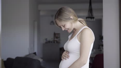 medium shot of smiling expectant mother rubbing belly