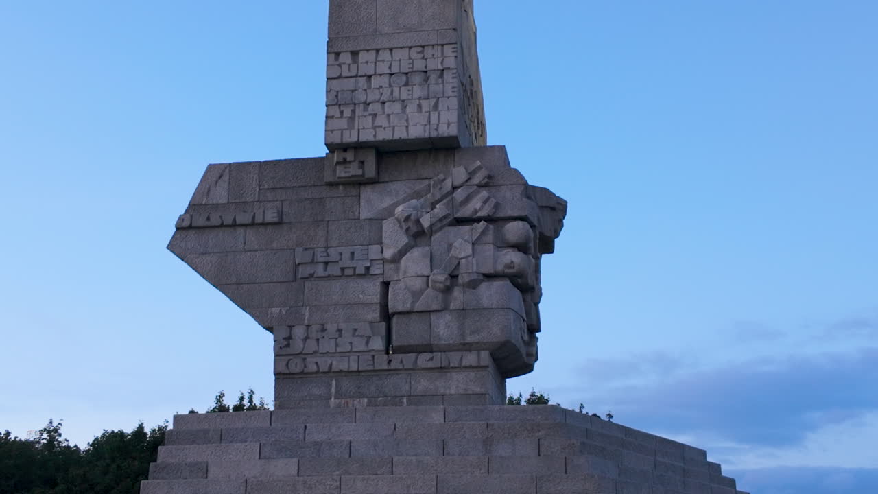 Close-up view of the granite reliefs and engraved names of Polish battle sites on the side of the Westerplatte Monument. Monument with engraved inscriptions and faces, symbolizing memory and courage