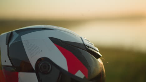 un primer plano de una mano con una pulsera verde, limpiando suavemente un casco de motocicleta