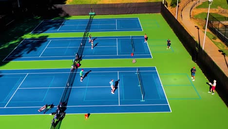 aerial drone shot slowly tilting down over pickle ball players on a tennis court having a tournament in atlanta, georgia