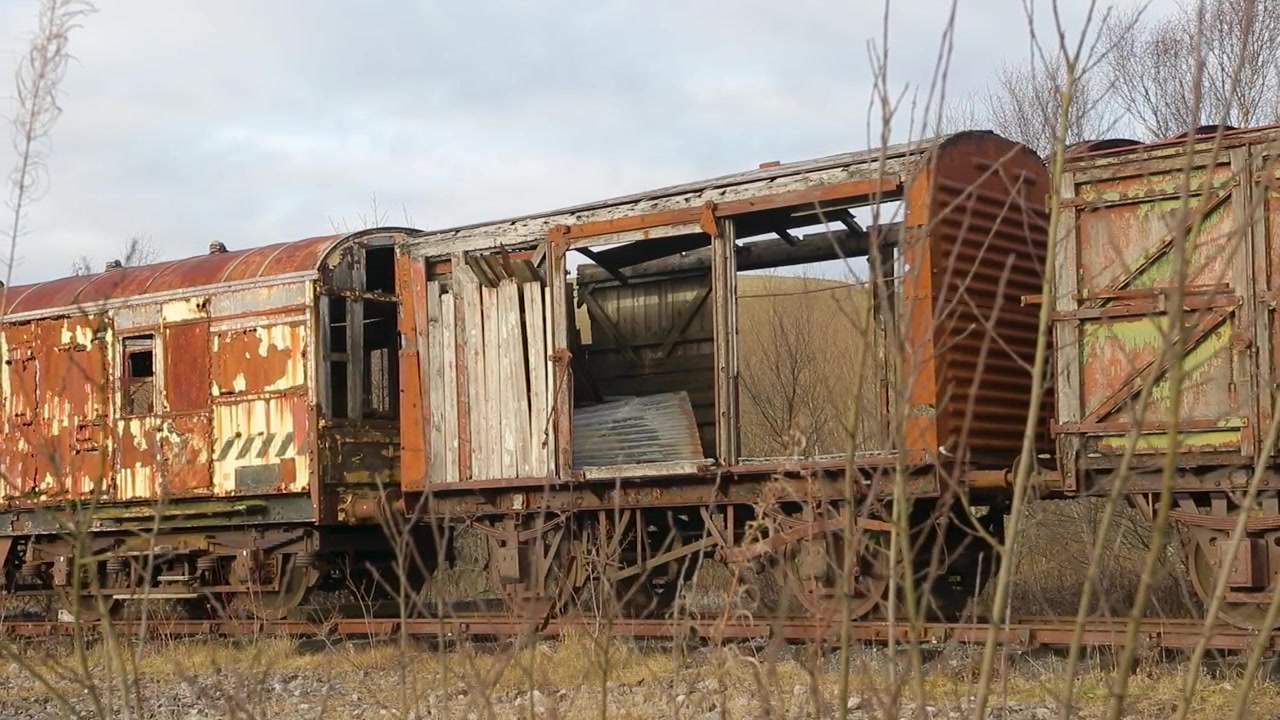 Weathered freight wagon with broken doors sits abandoned, perfect for urbex