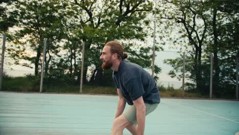 Ein-Rothaariger-Mann-In-Einem-Grauen-T-Shirt-Dribbelt-Einen-Orangefarbenen-Basketball.-Seine-Gegner-Versuchen,-Ihm-Den-Ball-Wegzunehmen,-Aber-Die-Männer-Schaffen-Es,-Ihn-Zu-Schützen