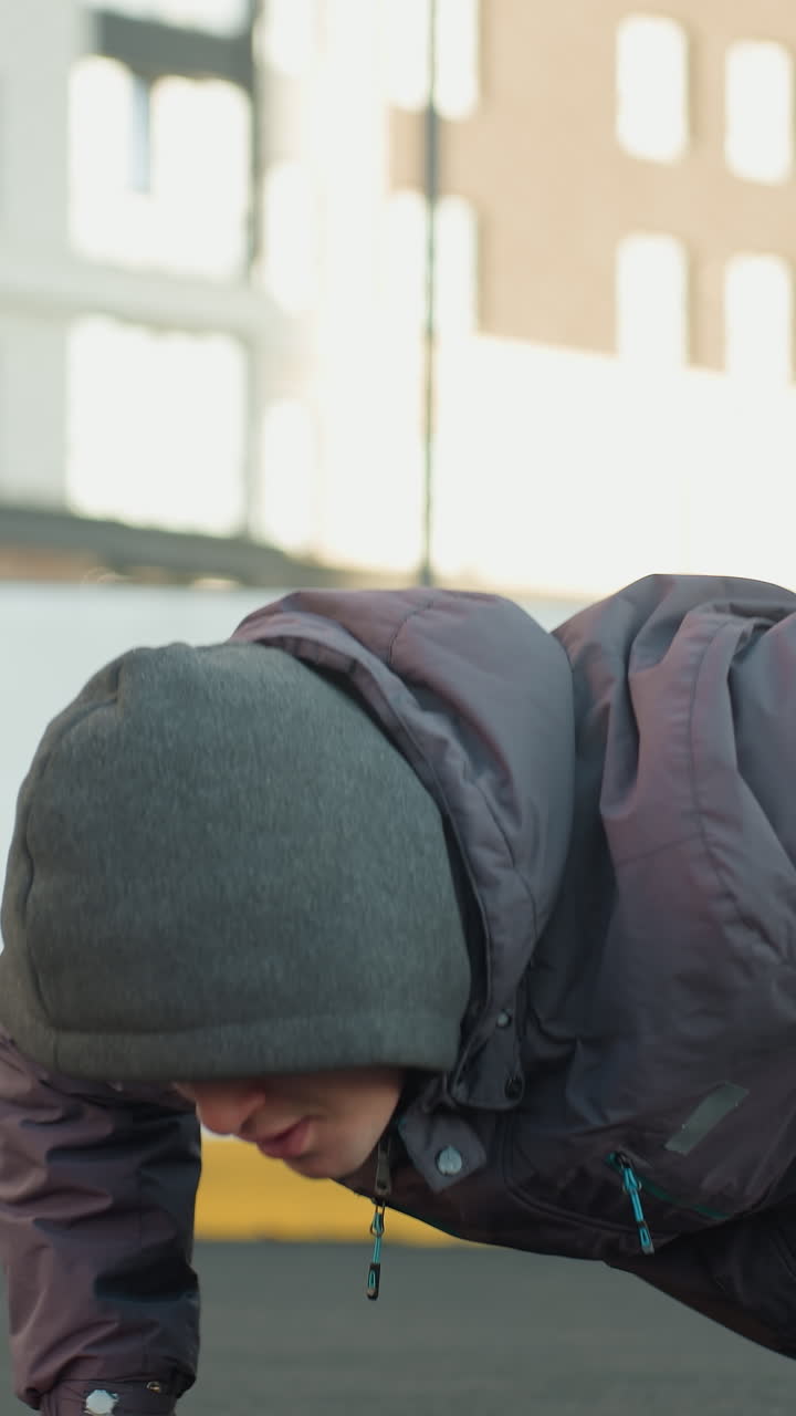 축구공에 손을 번갈아 놓고 푸시업을 하는 남자 야외 도시 경기장에서 힘, 조율, 민함을 보여주는 주거 건물 배경