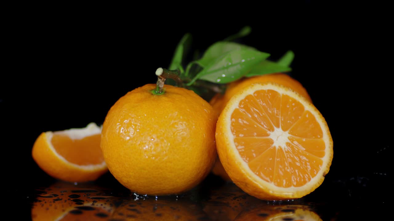 Mandarini con foglie e gocce d'acqua in caduta