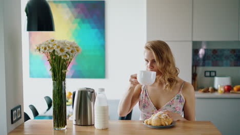 Happy-girl-having-breakfast-in-kitchen-at-home.-Beautiful-caucasian-woman