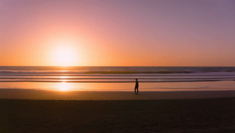 person walking on a beach at sunset