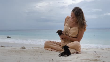 Toma-En-Cámara-Ultra-Lenta-De-Una-Mujer-Caucásica-Feliz-Jugando-Con-Cachorros-En-Una-Playa-Tropical-En-La-Isla-De-Asu,-En-El-Norte-De-Sumatra,-Indonesia