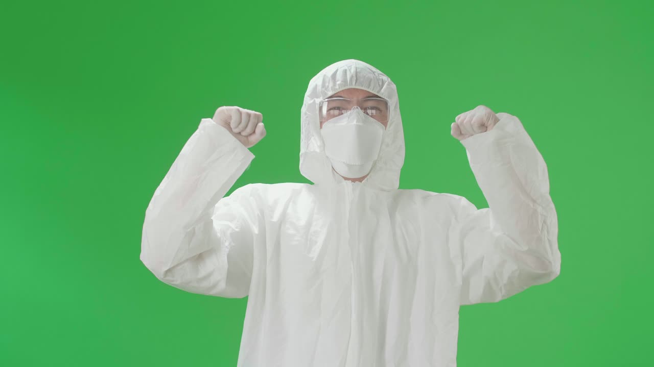 Asian Man Wearing Personal Protective Equipment Uniform Ppe, Medical Face Mask And Celebrating In The Green Screen Studio