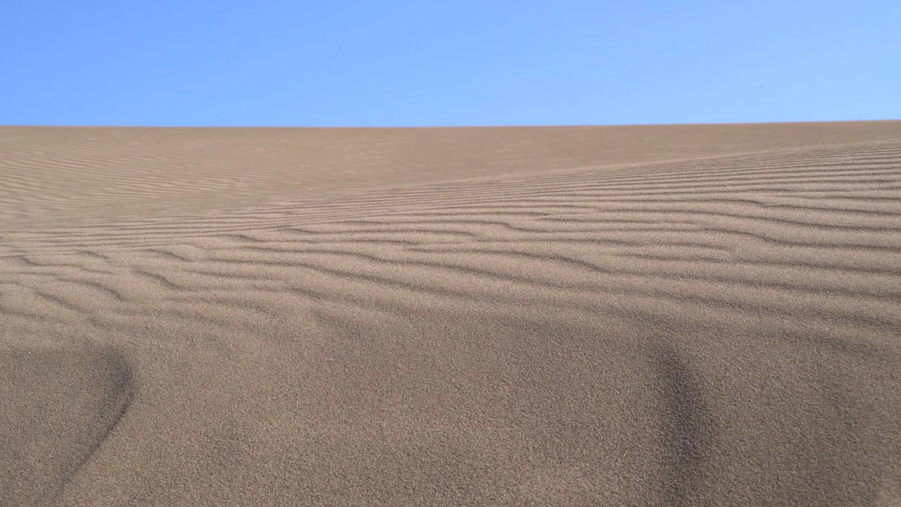 Dune di sabbia ondulate sotto un cielo azzurro sereno