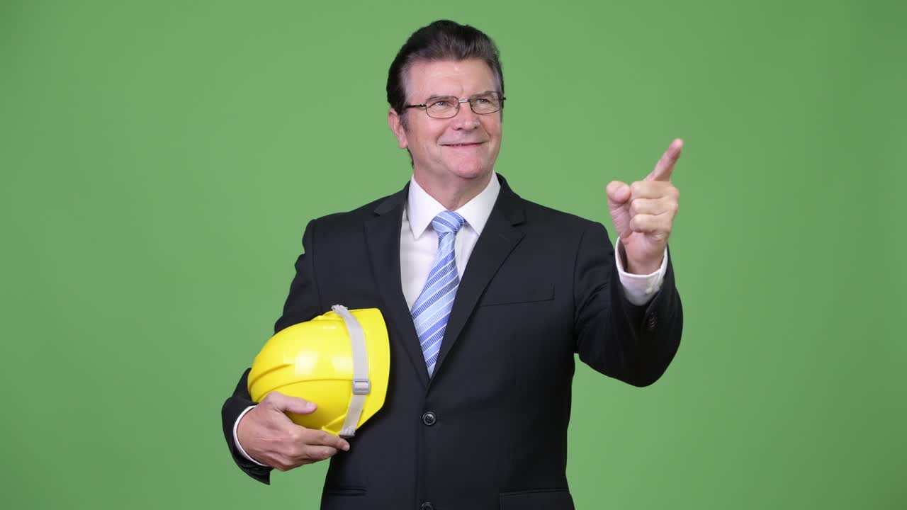 Senior handsome businessman as engineer pointing finger