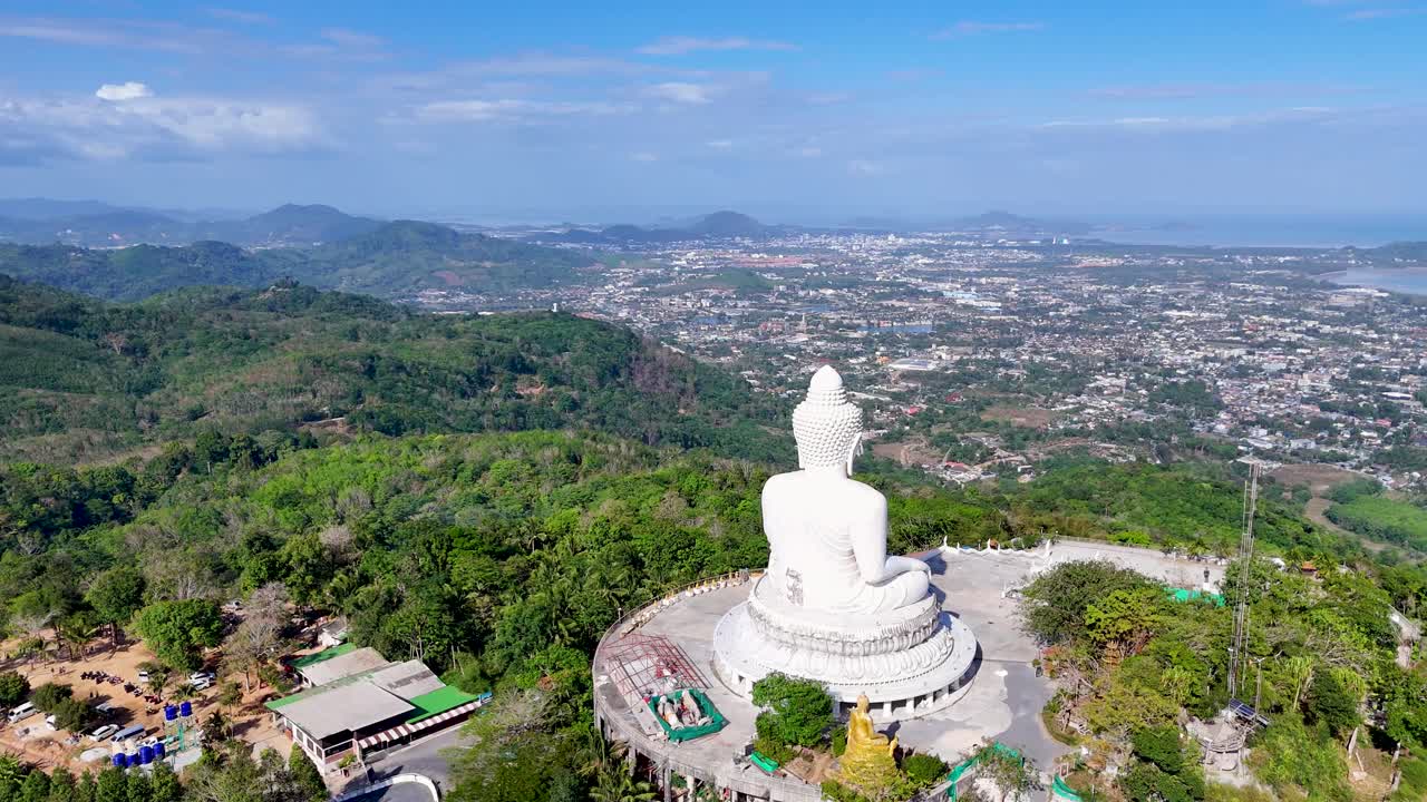 las imágenes de drones capturan la serena estatua del gran buda con vistas a paisajes exuberantes y paisajes urbanos lejanos en phuket, tailandia