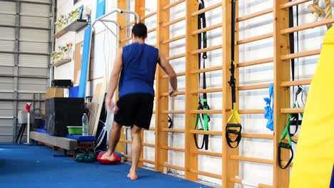 a still shot of a guy doing pistol squats inside a gymnastics gym