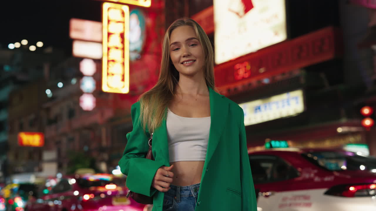 Giovane donna con un blazer verde in una vivace città di notte