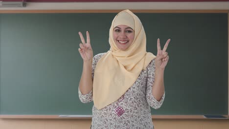 happy muslim teacher showing victory sign